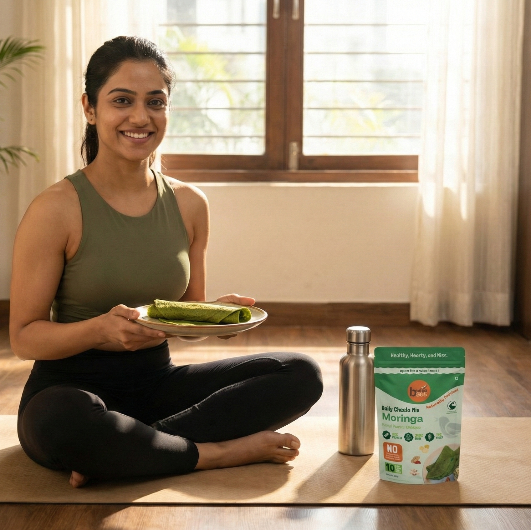 Woman sitting on a yoga mat holding a plate with a green smoothie, next to a container of Vega protein powder.